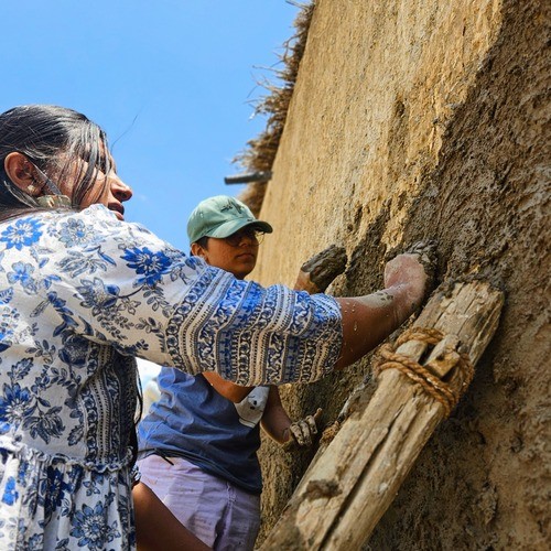 Base plaster application during natural building workshop in India